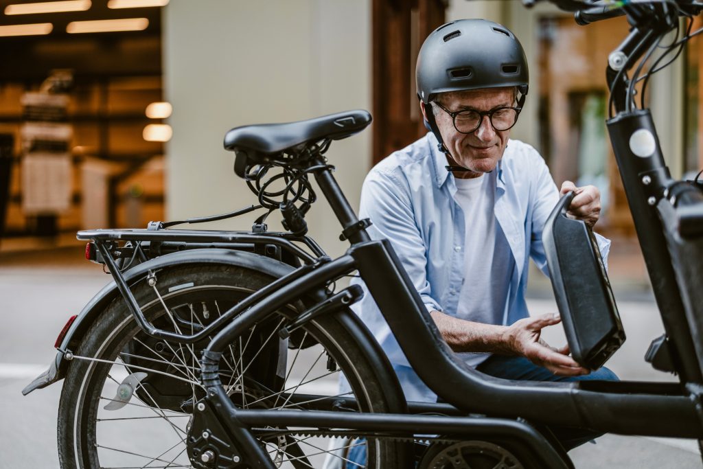 un homme enlève la batterie de son vélo électrique